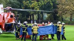 Пожарные и спасатели перевозят Ирис Штальцер, новоизбранного бургомистра Хердекке, на носилках перед тем, как разместить ее в вертолете