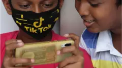 দুই বালক মোবাইল ফোন দেখছে।