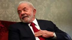 Lula sentado em sala, olhando para o lado e sorrindo