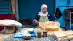 müslüman, başörtülü bir kadın yufka yapıyor. 