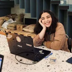 Parnia Abassi sonríe. Está sentada en una barra en una cafetería frente a su computadora