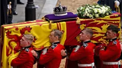 గ్రెనాడియర్ గార్డ్స్‌లోని ఎనిమిది మంది యువకులకు క్వీన్ శవపేటికను వెస్ట్‌మినిస్టర్ ప్యాలెస్‌లోకి తీసుకెళ్లే బాధ్యతను అప్పగించారు.