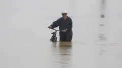 Hombre en biccleta en medio de una inundacion