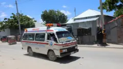Une ambulance est vue près d'un site d'explosion qui a secoué une base militaire à Mogadiscio