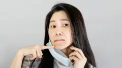 마스크 아래 여드름을 가리키는 여성