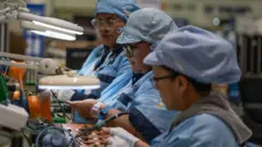 Tres mujeres en una fábrica de componentes eléctricos en México.