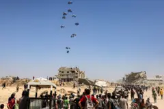 Palestinos observan un avión militar que lanza ayuda humanitaria -de Emiratos Árabes y Jordania- sobre el norte de la Franja de Gaza el 27 de julio de 2025.