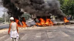 বিক্ষোভকারীরা সড়কে টায়ার জ্বালিয়ে নিরাপত্তা বাহিনীর কাছ থেকে নিজেদের আলাদা করে রেখেছে
