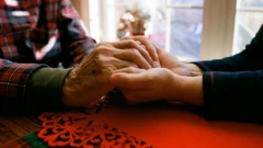 Mãos de uma pessoa idosa segurando as mãos de alguém mais jovem