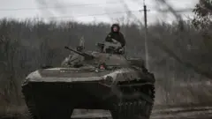 Ukrainian servicemen on a BMP-2 tank drive towards Bakhmut on 11 March