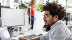 Homem de óculos usando computador