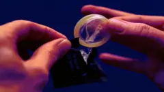 Person removing condom from packet, close-up - stock photo