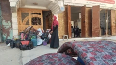 نوارة، امرأة أربعينية من غزة تقف أمام كومة من الأدباش والأغطية المحزومة بجوار قنينة غاز ومواعين وبراميل مياه، وأربعة أفرشة، تنتظر سيارة تنقلها هي وأطفالها الخمسة وأمتعتهم إلى جنوب القطاع. 