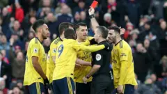 Referee raises a red card to Arsenal players