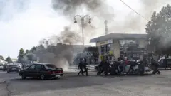 Yanan maşını itələyən insanlar