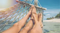 A couple lie in a hammock on an Indinesian beach