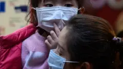 Hong Kong'da yüzlerine maske takmış bir anne ve kızı