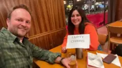Belén sentada en un pub con un desconocido