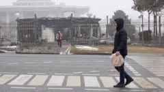A man walks in front of a the burned out presidential building in Almaty