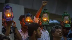Demonstrators hold placards and oil lamps as they protest against the recent electricity crisis in Dhaka, Bangladesh on 25 July 2022.