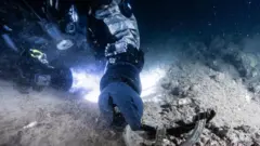 Un buzo apunta a una marca de la marina estadounidense en los restos de USS Eagle