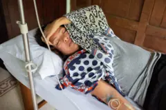 Mulher deitada, recebendo soro na veia