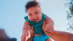 Mãos segurando um bebê no alto