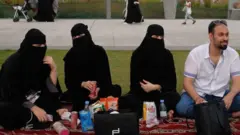 Tres mujeres completamente cubiertas de negro en Arabia Saudita, acompañadas de un hombre.