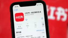 A mobile phone shows the APP interface of Xiaohongshu