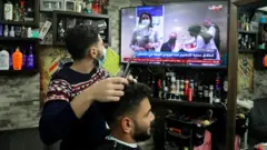 Un barbier regardant les nouvelles de Covid-19