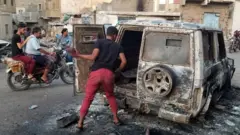 File photo showing a man looking at a burnt car in the Yemeni city of Taiz on 23 March 2019