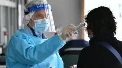 Nhân viên y tế kiểm tra thân nhiệt một phụ nữ tại Bệnh viện Công chúa Margaret ở Hong Kong