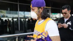 A Kobe Bryant fan wears a mask to his memorial service in LA on Monday