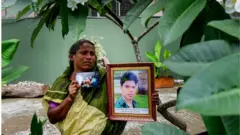 ছেলের ছবি হাতে নিয়ে এক নারী