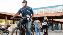 Homem anda de bicicleta segurando um caderno