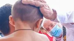 Lula coloca a mão na cabeça de uma criança indígena