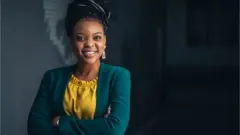 Une jeune femme pose fièrement dans son bureau