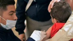 Un hombre aplica una vacuna a un niño