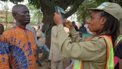 Un membre du National Youth Service Corps (NYSC) prend la photo d'un électeur à l'aide du système d'accréditation bimodal des électeurs (BVAS) lors de l'élection présidentielle du Nigeria, à Lagos, au Nigeria, le 25 février 2023.