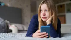 Una adolescente con su celular en la mano.