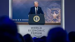 El presidente estadounidense Donald Trump aparece en una gran pantalla durante su intervención por videoconferencia en la reunión anual del Foro Económico Mundial en Davos, el 23 de enero de 2025. 