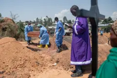 Um sacerdote realiza uma cerimônia de bênção no cemitério de Mbiyo para o quarto órfão que morreu de doença pelo vírus Ebola em um orfanato em Bunia, província de Ituri, em 19 de junho de 2026.