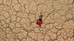 شاب يمشي على تربة متشققة وجافة في منطقة الأهوار في محافظة ميسان جنوب شرق العراق