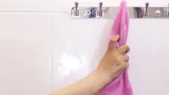 A stock image of a woman reaching for a towel