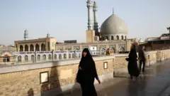 File photo showing people walking past the shrine of Fatima Masumeh in Qom, Iran (9 February 2020)