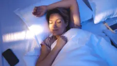 صورة تعبيرية تظهر امرأة نائمة ومبتسمة.