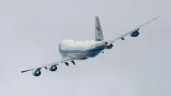 Um avião voando em meio a céu cinza