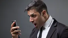 Um homem olha com surpresa para um telefone celular