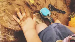 Mão de menino brincando com terra