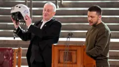 Umukuru w'inteko ishingamategeko y'Ubwongereza umutwe w'abadepite, Lindsay Hoyle, ubwo yari amaze guhabwa impano na Volodymyr Zelensky 